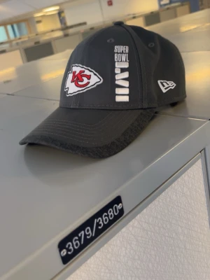 Kansas City Chiefs Super Bowl keps - Snygg svart keps från New Era med Kansas City Chiefs-logga och Super Bowl LVII-brodyr framtill. Modellen är 9FORTY med böjd skärm och justerbar passform. Perfekt för NFL-fans som vill visa sitt stöd med stil.