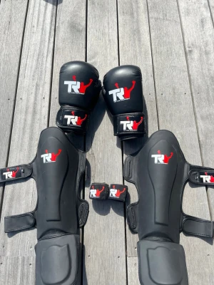 Boxningsset från Top Rank Equipment - Säljer ett komplett boxningsset med svarta boxningshandskar, benskydd och handledslindor. Allt är knappt använt och har inga skador. Ställ gärna frågor! Priset inte hugget i sten 