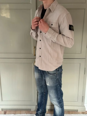 Stone Island Overshirt Beige/Vit - Extremt fet overshirt från Stone Island 😮‍💨          Den har en vitbeige färg, riktigt snygg | På lappen är det storlek L, men passar M mycket bättre. DM för mått (modellen: 181cm, ca 68-71kg)📏 | Skicket är som nytt,lapparna är av men de medföljer vid köp ✅ 