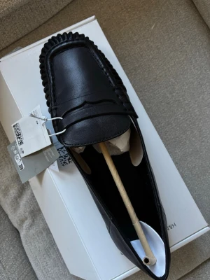 Svarta rynkade loafers i läder från H&M - Slutsålda loafers från H&M i äkta skinn heöt nya med prislappen kvar storlek 39 men stora i storlekeken. klassisk pennyloafers-design. Skorna har markerade sömmar runt tån och en låg klack. 