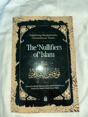 The Nullifiers of Islam bok - En bok med titeln 'The Nullifiers of Islam' med svart och beige omslag, dekorerad med arabiska mönster och text. Boken är skriven av Shaykh Muhammad bin Abdul Wahhab och förklarad av Shaykh Abdul'Aziz ar-Rajihi.