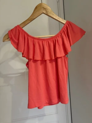 Korall offshoulder topp med volang - Snygg korallfärgad offshoulder topp med bred volang runt hela ringningen💞
