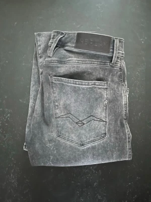 Replay Anbass Grå - Säljer ett par grå slim fit jeans från Replay då de har blivit för små för mig. Jeansen är slim och i gott skick. Skriv och fråga vid funderingar!