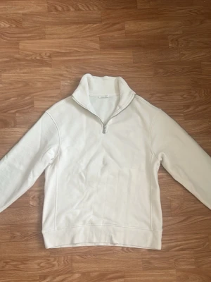 Zara Vit stickad tröja med halv dragkedja - Snygg vit stickad tröja med halv dragkedja och hög krage. Tröjan har långa ärmar och en stilren, minimalistisk design. Perfekt för lager-på-lager och passar till många olika outfits.