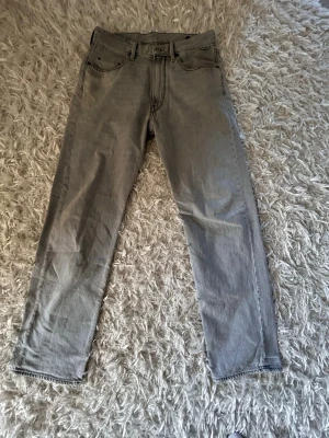 Grå jeans från G-Star RAW - Snygga grå jeans från G-Star RAW med raka ben och klassiska bakfickor. Jeansen har en tvättad look och detaljerad sömnad på fickorna. Tillverkade i denim med en cool streetkänsla och diskret logotyp på bakfickan.