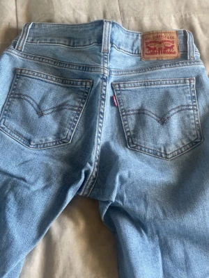 Ljusblå Levi's jeans med raka ben - Säljer ett par klassiska ljusblå jeans från Levi's med raka, utsvängda ben och femficksmodell. Jeansen har Levi's ikoniska läderpatch bak i midjan och röda logotag på bakfickan. Perfekta till en avslappnad stil och passar till det mesta.