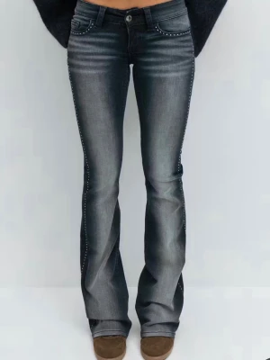 Grå bootcut jeans med nitar Gina tricot young 14+ - Snygga grå bootcut jeans med slitningar och coola nitar längs sidorna. Femficksmodell med knapp och dragkedja framtill. Jeansen har en lätt tvättad look och utsvängda ben för en trendig siluett.