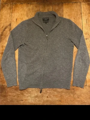 Grå merino/ kashmir ziptröja  - Mysig grå ziptröja från Savile Row Company i en lyxig blandning av merinoull och kashmir. Tröjan har hel dragkedja, ståkrage och ribbade muddar. Perfekt för lager-på-lager och en stilren look.