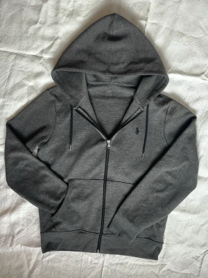 Mörkgrå hoodie Polo Ralph Lauren | XS - Mörkgrå hoodie med dragkedja från Polo Ralph Lauren | Strl: XS | Skick: Bra, förutom att labeln saknas, därav priset | Hör av dig vid funderingar ⁉️
