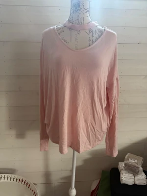 Ljusrosa långärmad topp - En enkel och mjuk ljusrosa långärmad topp med rund halsringning. Toppen har en avslappnad passform och är tillverkad i ett tunt, skönt material som passar perfekt till jeans eller kjol.