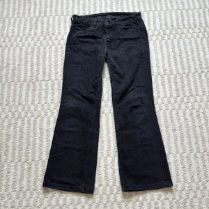 Svarta bootcut jeans Tommy Hilfiger - Svarta jeans från Tommy Hilfiger i modellen New York 71 med bootcut passform. Snygga bakfickor med broderad detalj. Några sömmar på ena fickan har gått upp (se bild), men annars i bra skick! Tillverkade i Italien i stretchigt jeanstyg. Köpta på Vinted, men aldrig använda av mig.                       Mått: Midja: 37cm (mätt platt)                                         Innerben: 67cm                                                                                Hela längden: 93cm