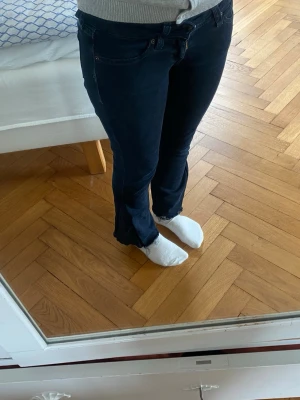 Mörkblå bootcut jeans från Levi's - Säljer ett par svarta bootcut jeans från Levi's med klassiska fem fickor och råa, fransiga benslut. Jeansen har en figurnära passform upptill och släpper ut vid vaden. Perfekta för en avslappnad och trendig look. De är omsydda från skinny till bootcut om du vill ha närbild så fråga gärna 