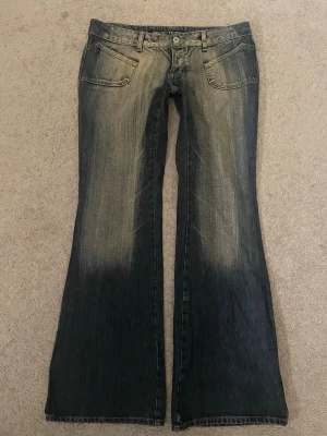 2000s Bootcut low waist jeans - Snygga bootcut jeans i mörkblå denim med slitna detaljer och ljusa partier framtill och baktill. Jeansen har klassiska fem fickor och låg midja. Perfekta för en avslappnad och trendig look.