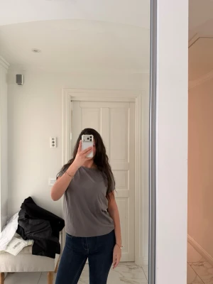 Grå basic t-shirt  - En stilren grå t-shirt med rund hals och korta ärmar. T-shirten har en enkel design utan mönster och är tillverkad i ett mjukt material som känns skönt mot huden. Perfekt till jeans eller shorts.