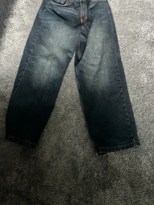Mörkblå loose fit jeans - Säljer ett par mörkblå loose fit jeans med snygg tvättad look och raka ben. Jeansen har klassiska fem fickor och kontrastsömmar. Perfekta för en avslappnad och trendig stil.