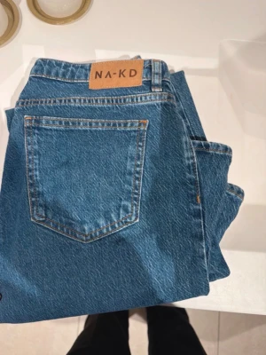 Blå raka jeans från NA-KD - Snygga blå jeans från NA-KD med klassisk femficksdesign och raka ben. Perfekta för en avslappnad och trendig look.Jag har sytt upp de så långt mässigt passar de mig som är 1,65. Men det går att sprätta upp om man vill det💗