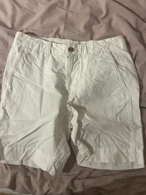Vita bomullsshorts med fickor - Snygga vita shorts i bomull med normal passform. Klassisk design med sidofickor och bakfickor, samt knapp och dragkedja framtill. Perfekta för varma dagar och enkel att matcha med olika stilar.