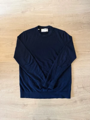 Mörkblå tröja från Selected - En stilren mörkblå tröja från Selected med rund halsringning och långa ärmar. Perfekt för lager-på-lager och enkel att matcha med olika outfits. Tröjan har en klassisk passform och är tillverkad i mjukt stickat material.