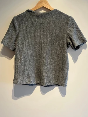 Grå ribbad kortärmad topp - En stilren grå ribbad topp med korta ärmar och rak passform. Mjuk och bekväm, passar till många olika outfits.🌟