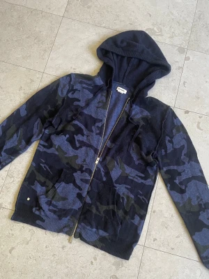 Zadig & Voltaire Zip Hoodie Camo - Tja! Säljer denna feta zip-hoodien från Zadig & Voltaire i bra skick. Unikt kamouflage i blått och kashmir/ull mix som gör den sjukt bekväm och stilren! || Skick: 7.3/10, endast lite pösig i armarna och 3 mindre hål i luvan (Inget som påverkar helhetsintrycket!) || Storlek: M, passar även L || Tveka inte på att höra av dig vid frågor eller prisförslag!😊✌️