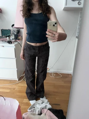Bruna cargobyxor med fickor - Säljer ett par bruna cargobyxor med flera stora fickor på sidorna och framtill. Byxorna har en rak passform och är tillverkade i ett mjukt, lätt material som känns bekvämt. Perfekta för dig som gillar en avslappnad och cool stil.