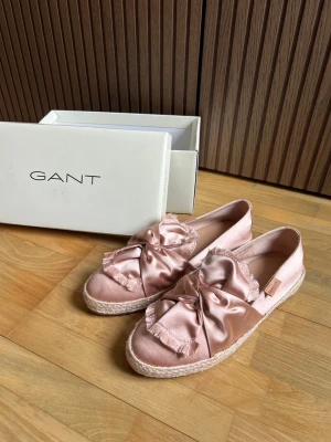 Rosa satinloafers med rosett från Gant - Snygga rosa loafers från Gant i satin med stor rosett och fransade kanter. Skorna är aldrig använda och kommer i sin orginallåda.