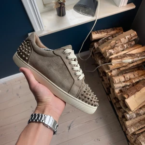 Christian Louboutin  - Säljer ett par gråbeige sneakers från Christian Louboutin i mocka med ikoniska röda sulor. Du får med dig dustbags box och kvitto.