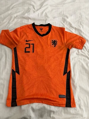 Holland fotbollströja Nike orange - Säljer en orange Holland fotbollströja från Nike med svarta detaljer, nummer 21 Frenkie De jong. Bra skick och inga problem med den. 