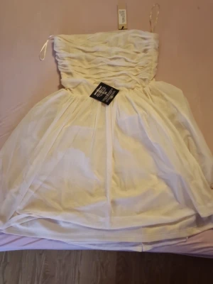 Vit Mimosa klänning från Nelly - Supersöt vit kortklänning från Nelly, modell Mimosa Dress. Klänningen är axelbandslös med rynkad överdel och har ett tunt, luftigt tyg som ger en romantisk känsla. Perfekt för sommarens alla tillfällen! Helt ny med prislapp! Priset kan diskuteras❤️🫶🏼