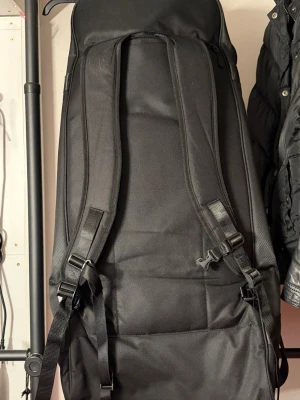 Svart Unihoc ryggsäck med spännen - Unihoc Goalie Backpack DARK LINE är en ryggsäck framtagen speciellt för innebandymålvakter som behöver mycket plats för sin utrustning. Den har en stor kapacitet på upp till 100 liter, vilket gör det enkelt att få med allt som behövs till träning eller match. Ryggsäcken är tillverkad av 100 % återvunna material, vilket gör den till ett mer miljövänligt alternativ.