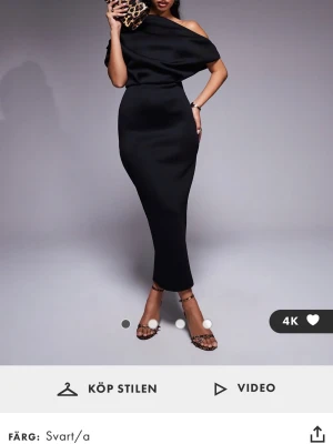 Svart oneshoulder långklänning -  Svart långklänning med oneshoulder-design. Klänningen har en smal passform och slits bak. Klänningen är endast använd en gång och är som ny. Nypris är 869kr.