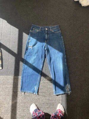 Blåa jeans Sweet SKTBS Big Skate Backprint jeans - Unika blåa jeans med raka ben och slitna detaljer. Baksidan har stort gult tryck med texten 'Sweet Sk8boys' i gotisk stil. Jeansen har klassisk femficksdesign och råa kanter vid bensluten. Perfekta för dig som gillar streetwear och skatekultur.