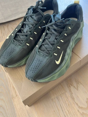 Nike Ava Rover NYA - Snygga svarta Nike sneakers med vågig grön sula och gula detaljer ANVÄNDA 1 gång säljes pga köpt i fel storlek. Kartong medföljer!      Skorna har perforerad tå, klassisk snörning och en låg silhuett. Perfekta för dig som vill ha en unik och sportig look. Ikonisk Swoosh-logga på sidan och dragflik bak.