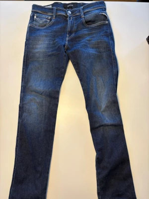 Mörkblå jeans från Replay - Snygga mörkblå jeans från Replay i storlek W30 L32 med klassisk femficksmodell och raka ben. Jeansen har broderade detaljer på bakfickorna. Perfekta för en avslappnad och trendig look.