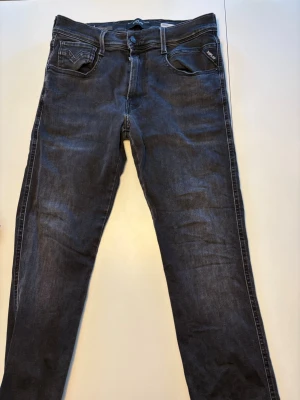 Svarta slim fit jeans från Replay - Snygga svarta slim fit jeans från Replay i storlek 30 32. Jeansen har normal midja, raka ben och är tillverkade i stretchigt denim för extra komfort. Liten slitning på insidan (syns på bild 3) men inget märkvärdigt alls