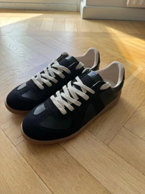 Maison margiela sneakers - Hej! Säljer ett par Maison Margiela sneakers i storlek 42. Skorna är i nyskick och är svartfärgad. Till skorna medföljer originallåda.