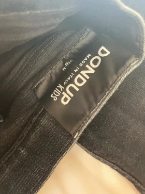 Svarta skinny jeans från Dondup - Säljer ett par svarta skinny fit jeans från Dondup, tillverkade i Italien. Jeansen har klassisk femficksdesign och är gjorda i stretchigt denimtyg för en tajt och bekväm passform. Perfekta för dig som gillar en stilren och modern look.