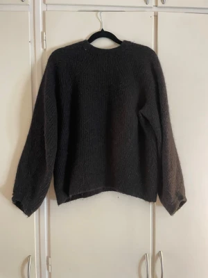 Svart  stickad tröja - Mysig svart stickad tröja med rund halsringning och långa ärmar. Tröjan har en enkel, rak passform och är tillverkad i ett fluffigt garn som ger en avslappnad look. Perfekt för kyliga dagar och enkel att matcha med jeans eller kjol. 