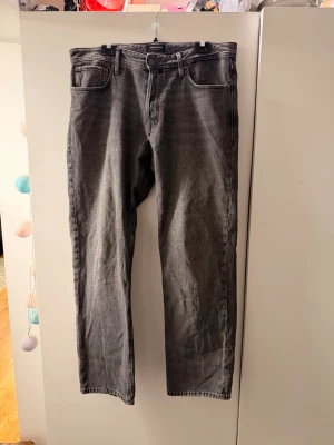 Grå raka jeans relaxed chris - Säljer ett par grå jeans från Jack & Jones modell relaxed chris storlek 36/34