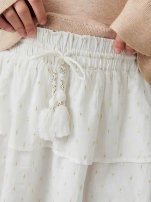 Jättefin kjol  - Superfin vit kortkjol med volanger och små guldiga detaljer. Kjolen har resår i midjan och dekorativa tofsar med pärlor framtill. Perfekt för en fräsch och somrig look. Från Gina tricot. Använd få gånger! Jättefin!!