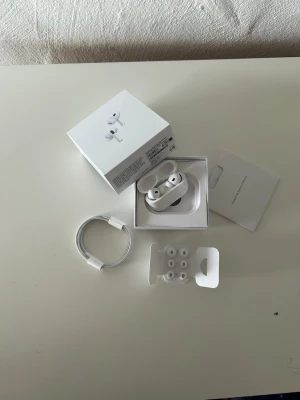 Apple AirPods Pro med laddningsetui - Säljer ett par vita Apple AirPods Pro med trådlöst laddningsetui. Inkluderar originalkartong, USB-C laddkabel, extra silikonpluggar i olika storlekar och manualer. Snygg och stilren design i plast, perfekt för dig som vill ha grymt ljud och brusreducering. Jag säljer de här eftersom att jag redan har ett par 