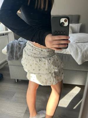 Vit blommig skort med volanger - Supersöt vit skort med små blå och gula blommor 💞