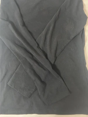 Svart långärmad basic topp - En enkel svart långärmad topp i mjukt bomullsliknande material. Perfekt att styla lager på lager eller bära som den är. Klassisk rund halsringning och rak passform som funkar till det mesta.