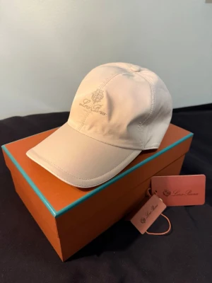 Beige keps från Loro Piana - Exklusiv keps från Loro Piana i en stilren ljus/beige ton med diskret broderad logga framtill. Tidlös och minimalistisk design som passar till allt.  • Helt ny • Storlek XL (ca 58–60 cm, upplevs som L) • Premiumkvalitet med hög komfort • Kommer med originalbox  En perfekt “quiet luxury”-accessoar som lyfter vilken outfit som helst.  📦 Snabb frakt Skriv vid frågor!