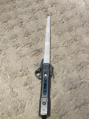 Blå och silverfärgad leksaksljussabel - Cool leksaksljussabel i blått, silver och vitt, perfekt för cosplay eller maskerad. Handtaget har futuristiska detaljer och ljussabeln kan fällas ut. Tillverkad i plast och passar utmärkt till sci-fi eller rymdtema.