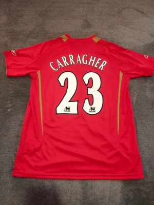 Liverpool Matchtröja | 2005-06 | Carragher - Liverpools Champions League tröja från säsongen 2005-06.  Carragher, nr 23 på ryggen. Stadium/fan edition. Ny & oanvänd. Storlek XL.  Tröjan är en replika i utmärkt kvalitet. Skickas 1-3 dagar efter mottagen betalning. Har du frågor/funderingar är det bara att höra av dig! :) kajhbskks