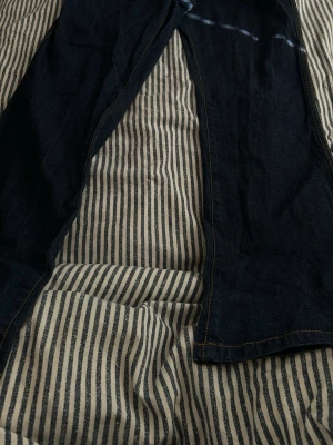 Mörkblå raka jeans - Säljer ett par mörkblå jeans med rak passform och klassiska kontrastsömmar. Jeansen har en tidlös look och är tillverkade i denim, perfekt för dig som gillar enkel och stilren stil.