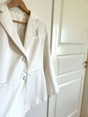 Vit kavaj med två knappar - Superfin kavaj i storlek M för en lite mer oversized men sofistikerad look! Använd vid få tillfällen men inga slitningar, maskor eller liknande Från NAKD
