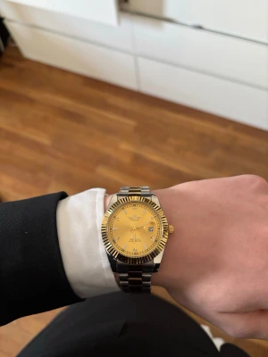 Rolex Day-Date Guld/Silver liknande - Rolex Day-Date Guld/Silver liknande. Den är stilren och passar till alla tillfällen. Helt ny. Om man skriver till mig så kan jag skicka med en länkbortagare.