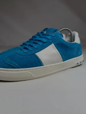 Valentino flycrew blå - Snygga sneakers i blå mocka med vita detaljer och vit sula. Skorna har klassisk låg profil och matchande blå skosnören. Perfekta för dig som vill sticka ut med färg på fötterna. Ovandelen är i mocka och textil, sulan är i gummi.